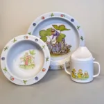 Blomsterbørn - en serie i rød/gul/blå. Den flade tallerken med blåt motiv, den dybe med rødt og kruset med gult og rødt., Elsa Beskow Dyb Tallerken - Blomsterbørn, Elsa Beskow Flad Tallerken - Blomsterbørn, Elsa Beskow Krus med Låg - Blomsterbørn, blomsterbarnen, blomsterfesten, blomsternes bog, astrid lindgren, billedbøger, eventyr, illustrationer, tegninger, tudkop, kop, krus, lågkrus, baby, babyshower, barnedåb, dåbsgave, barselsgave, svensk, nostalgisk, service, til børn, drikke, tud, biti, ribe