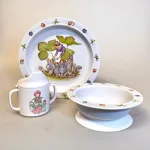 Blomsterbørn - en serie i rød/gul/blå. Den flade tallerken med blåt motiv, den dybe med rødt og kruset med gult og rødt., Elsa Beskow Dyb Tallerken - Blomsterbørn, Elsa Beskow Flad Tallerken - Blomsterbørn, Elsa Beskow Krus med Låg - Blomsterbørn, blomsterbarnen, blomsterfesten, blomsternes bog, astrid lindgren, billedbøger, eventyr, illustrationer, tegninger, tudkop, kop, krus, lågkrus, baby, babyshower, barnedåb, dåbsgave, barselsgave, svensk, nostalgisk, service, til børn, drikke, tud, biti, ribe