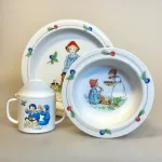 Elsa Beskow Dyb Tallerken - Putte i Blåbærskoven, Elsa Beskow Flad Tallerken - Putte i Blåbærskoven, Elsa Beskow Krus med Låg - Putte i blåbærskoven, blomsterfesten, blomsternes bog, astrid lindgren, billedbøger, eventyr, illustrationer, tegninger, tudkop, kop, krus, lågkrus, baby, babyshower, barnedåb, dåbsgave, barselsgave, svensk, nostalgisk, service, til børn, drikke, tud, biti, ribe