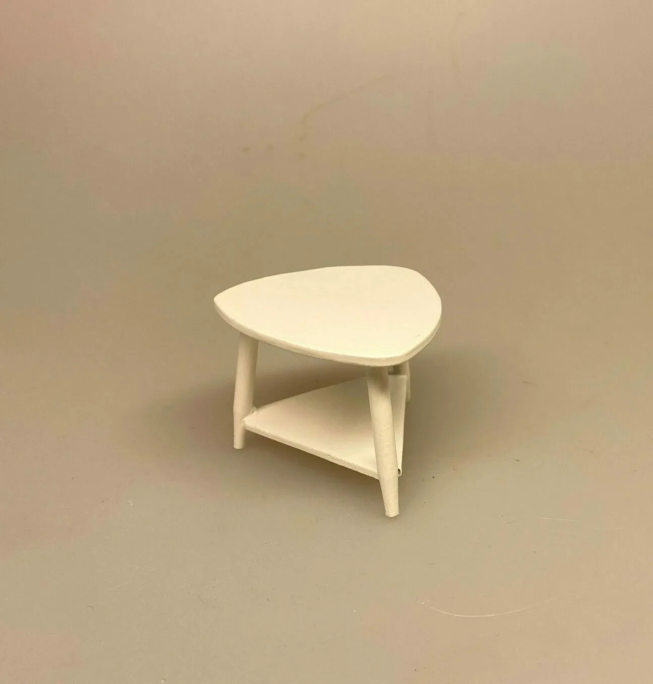 Miniature Trekantet hvidt sofabord med hylde Miniature Trekantet hvidt sofabord med hylde, sofabord, nyreformet, retro, bord, hjørnebord, lampebord, dukkehus, dukkemøbler, dukkestue, dukkehustilbehør, nisser, nissetilbehør, nisse, nissebo, nissehus, nissedør, tilbehør, ting, sangskjuler, symbolsk, gave, gavekort, til, bord, møbler, lille, miniature, mini, miniaturer, 1:12, biti, ribe, indretning, lege, dukkehusting, dukkehusmøbler,
