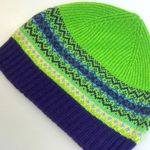 Hue Uld - Eribé Beanie Grøn Lilla, klare farver, knaldgrøn, græsgrøn, sirius, eribe, skotsk, farver, smart, tidsløs, klassisk, flot, lækker, kvalitet, uld, ren, ulden, tynd, blød, let,strikket, fintstrikket, skotsk, engelsk, design, country, side, biti, ribe, eribe, sort sol, vadehavet, marsken, gave, gaveide, julegave, efterår, vinter,