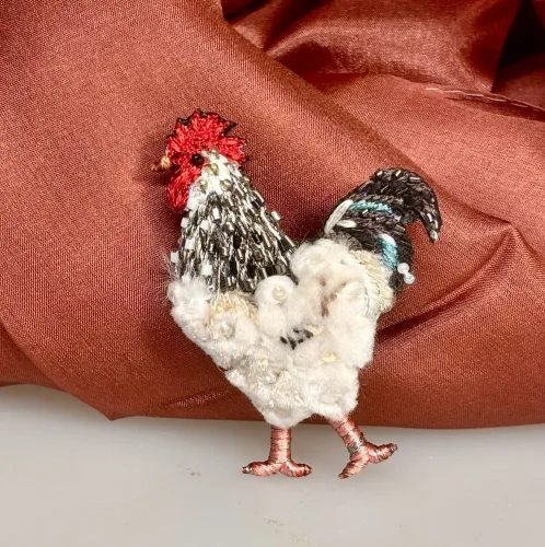 Håndlavet Broche Hane. høne, høns, hønsehold, hønsegård, rooster, kok, kokkemand, lys sussex, hane, smykke, broche, broderet, broderi, kunst, kunsthåndværk, kvalitet, unik, særlig, smuk, skønhed, gave, gaveide, hønseting, æggedame, æggekone, eventyrlig, ide, rund, fødselsdag, jubilæum, personlig, gave, julegave, biti, ribe, trovelore, broderibe, syteknik, perlebroderi